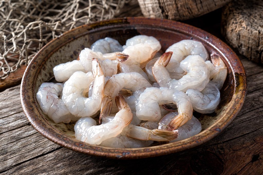 A bowl of fresh raw pacific white shrimp peeled with tail on