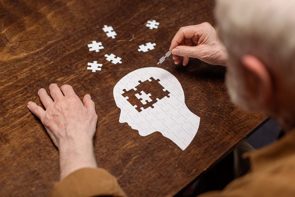 Senior man working on a puzzle of a human head 