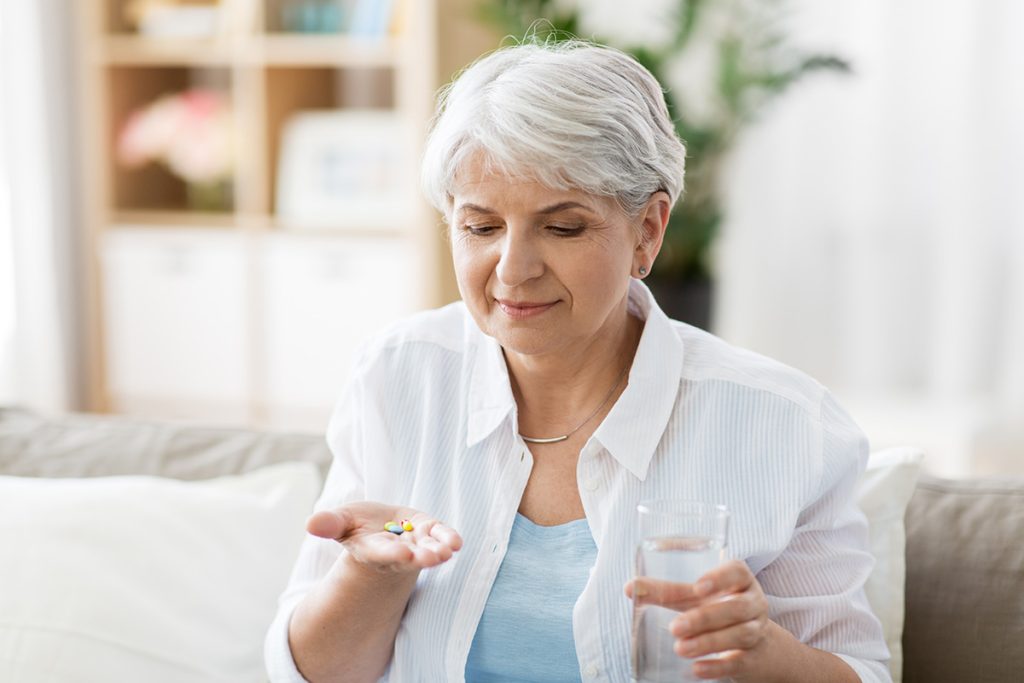 Older woman getting ready to take her daily vitamins on the couch in the living room