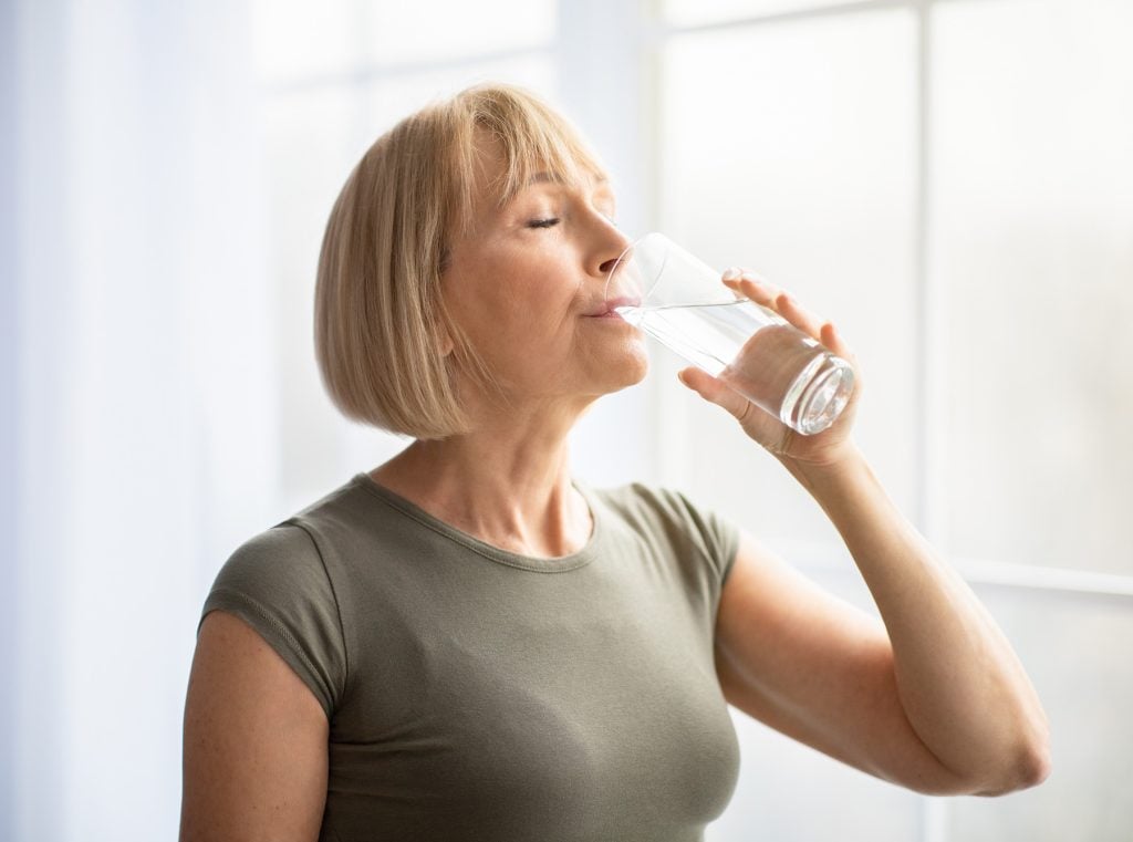 An older woman drinking a glass of water