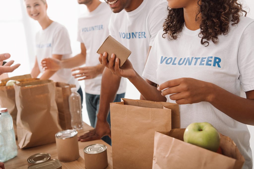 Volunteers placing fruits and cans in brown paper bags