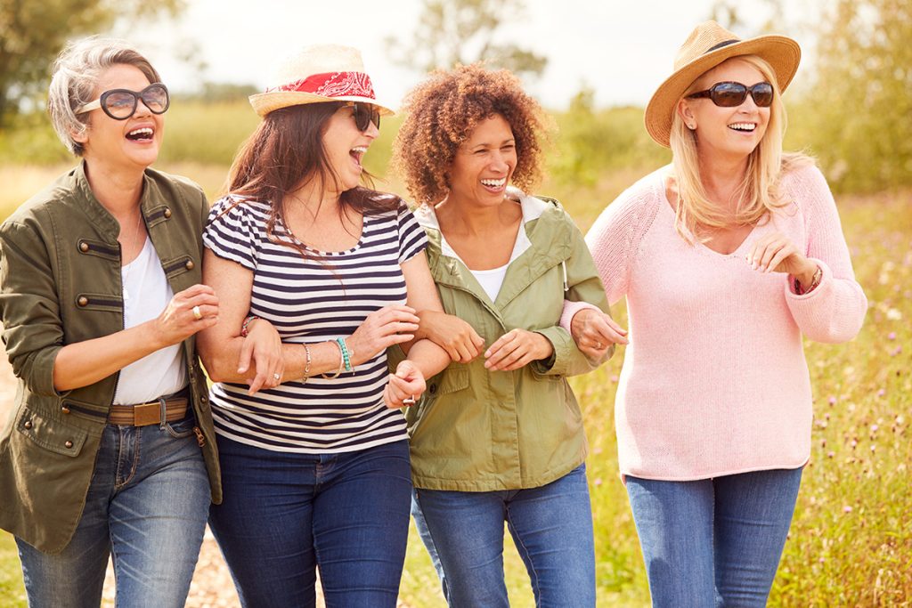 A group of women laughing and enjoying each other's company while walking in a park