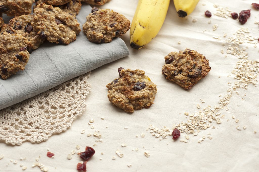 Close up of chocolate banana oatmeal cookies on a table with two bananas next to them