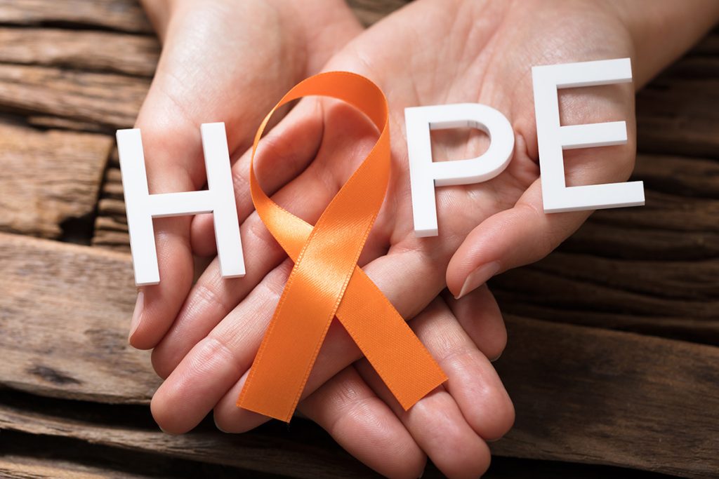 A pair of hands presenting letters that spell out "Hope" with an orange cancer ribbon as the "o"