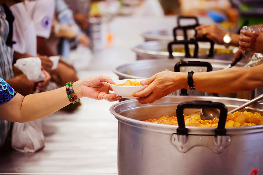 Close up of a volunteer's hand giving food to a woman