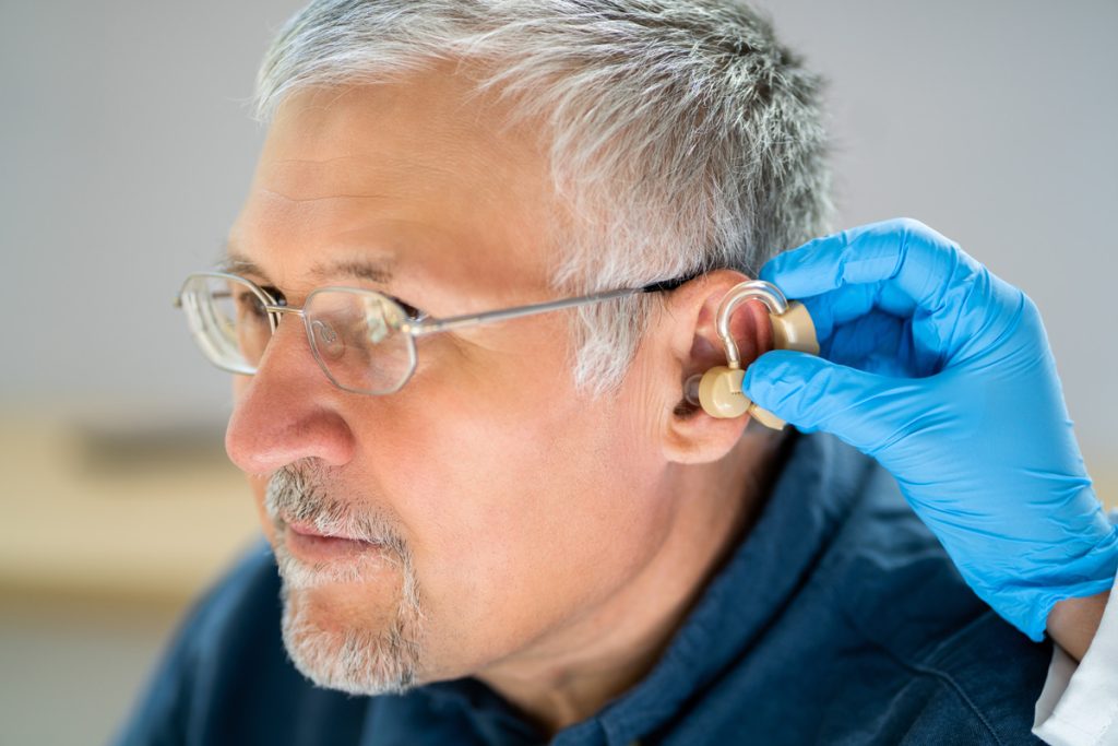 An older man having his ear checked by a doctor