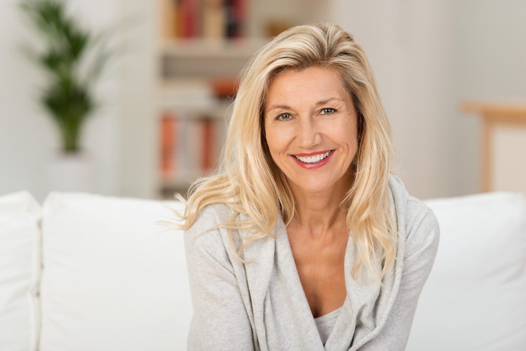 middle age woman on the couch smiling at camera