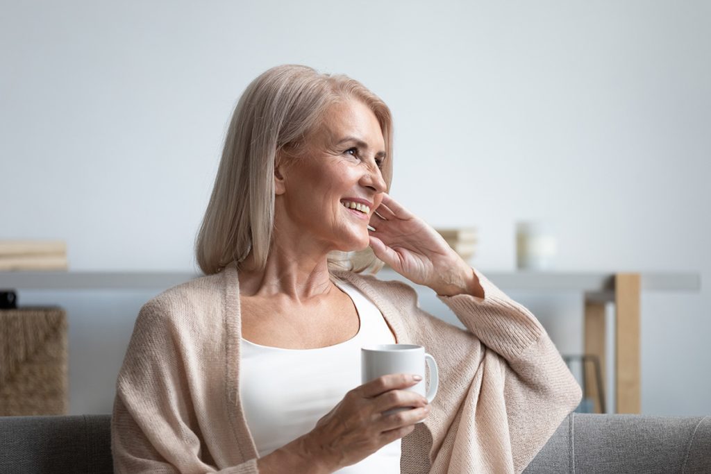 Older woman drinking tea and staring at window