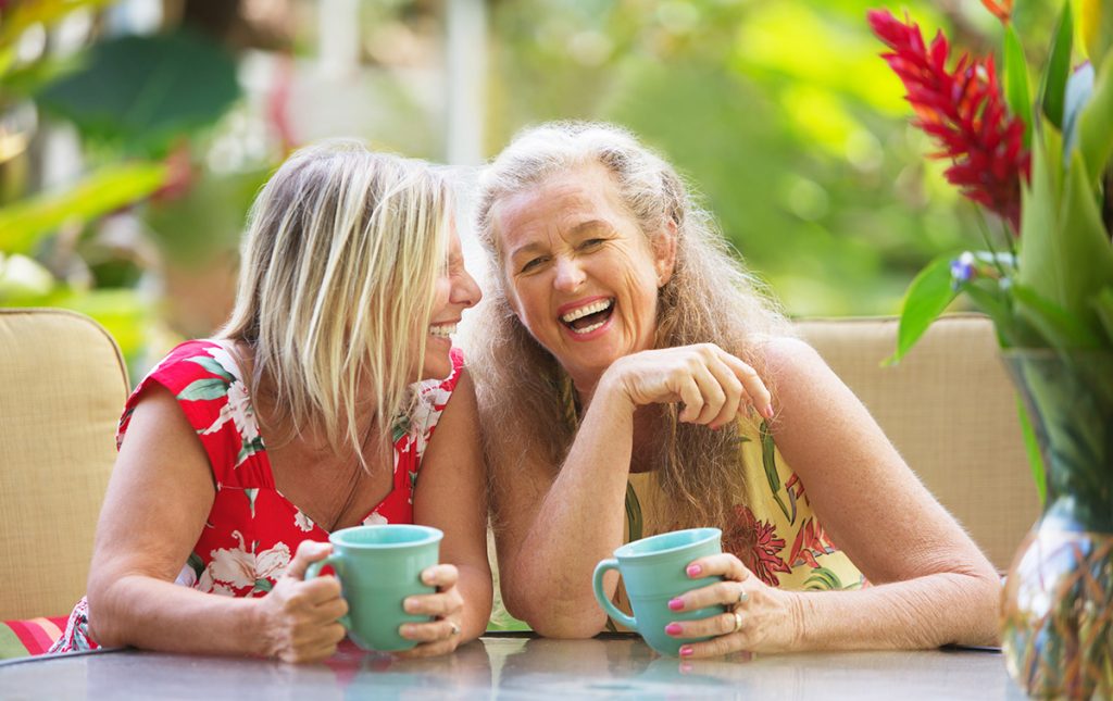 Two older female friends having tea and laughing