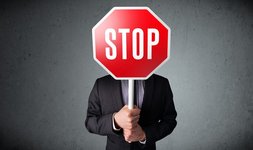 Man in suit holding up stop sign