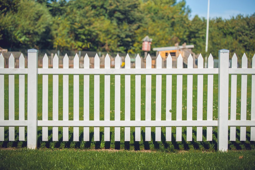White picket fence on green lawn