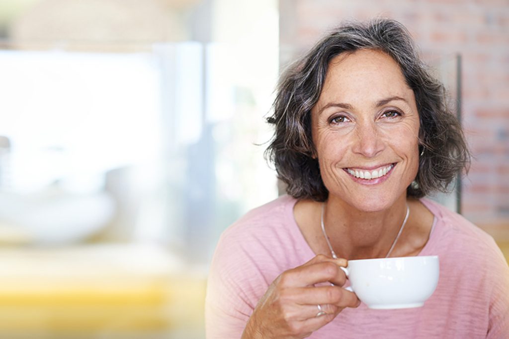 woman drinking coffee smiling at camera