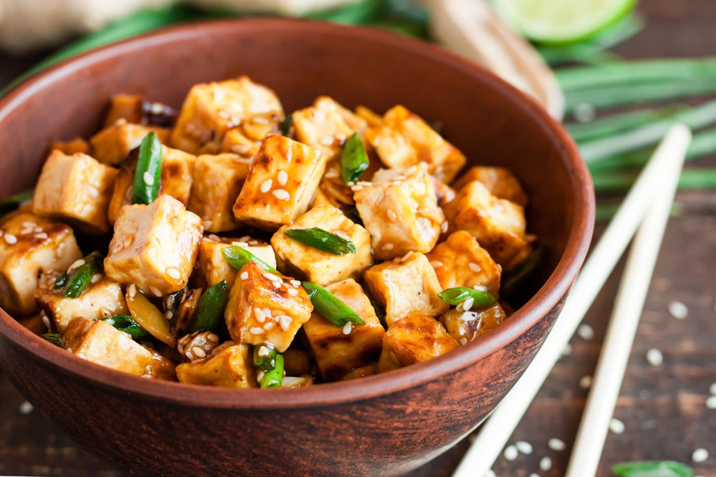 Cut up square tofu in a wooden bowl mixed with some sauce