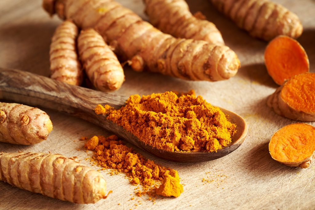 A spoon full of Curcumin and surrounded by turmeric