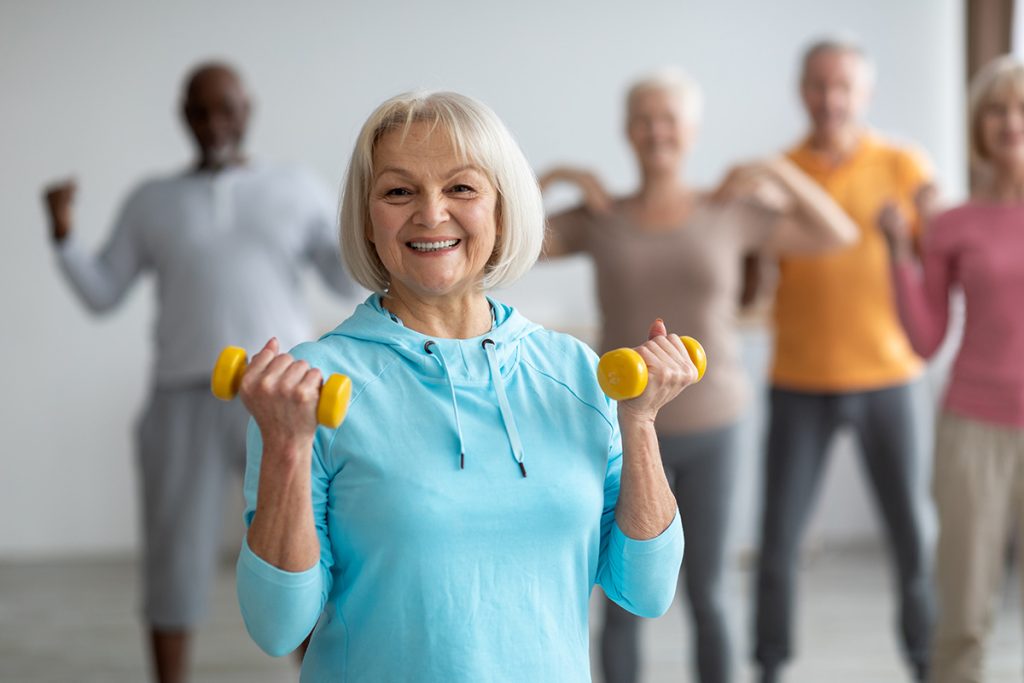 Senior woman lifting weights and smiling at camera