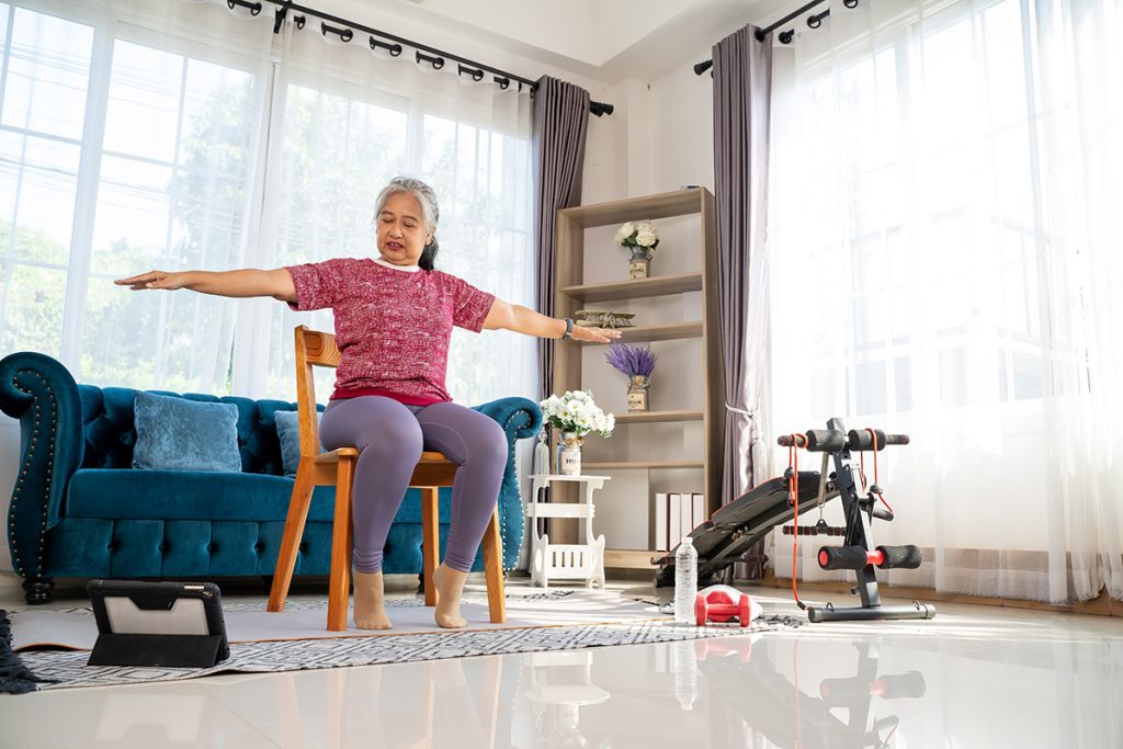 Older lady doing chair exercise in her living room