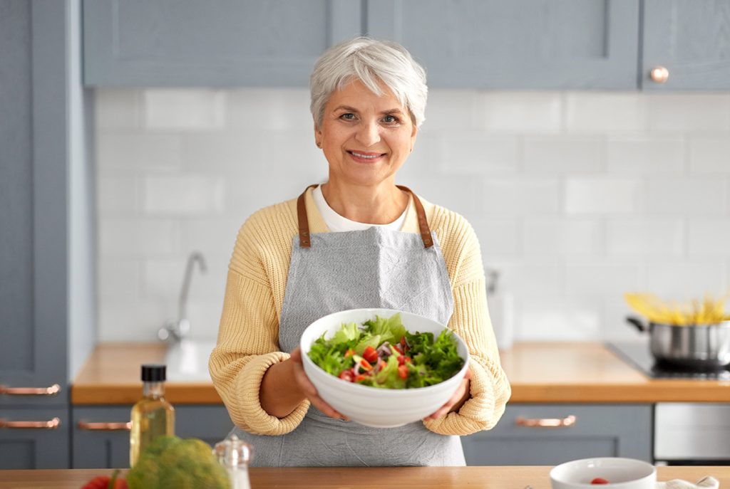 Older woman holding up a bowl of salad