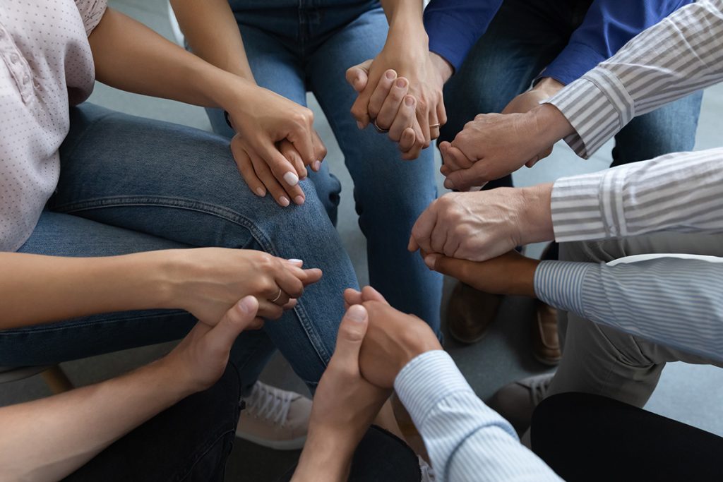 A group of people clasping their hands together in a circle