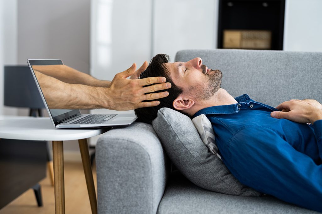 Man getting head massage from hands coming through laptop screen