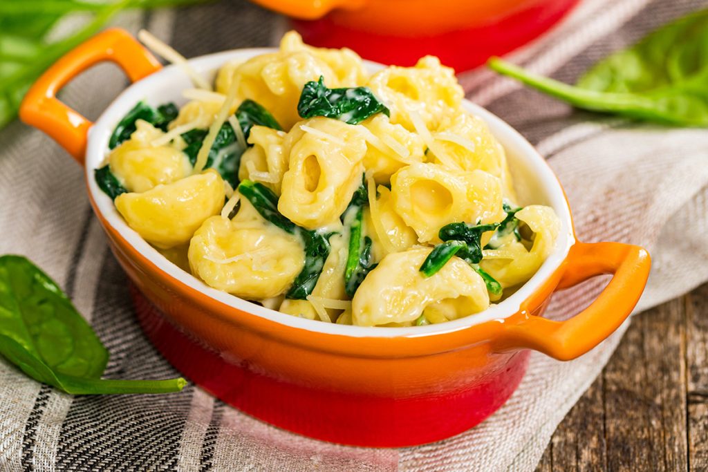 Vegan mac and cheese with spinach in a bowl on table