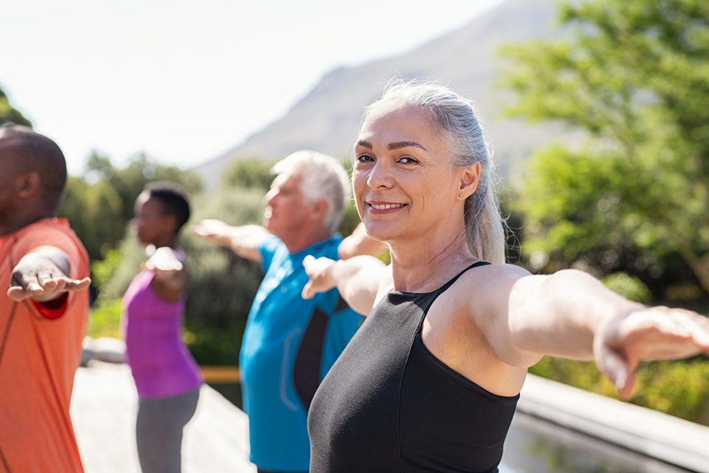 Older woman in a yoga class smiling and looking at the camera