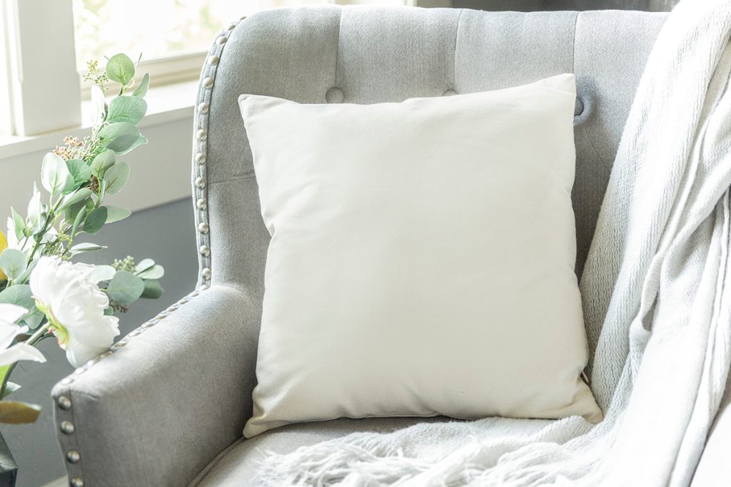 Cozy grey chair with plush pillow and a soft blanket