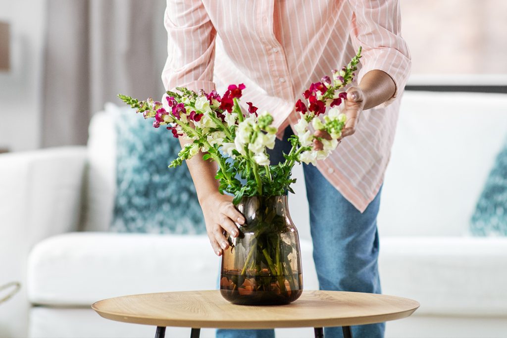 Woman placing flowers down on coffee table as decorations