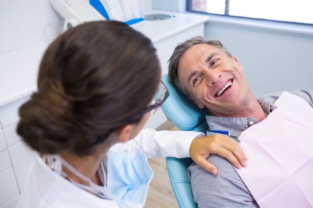 Middle age man smiling and enjoying a conversation with his dentist