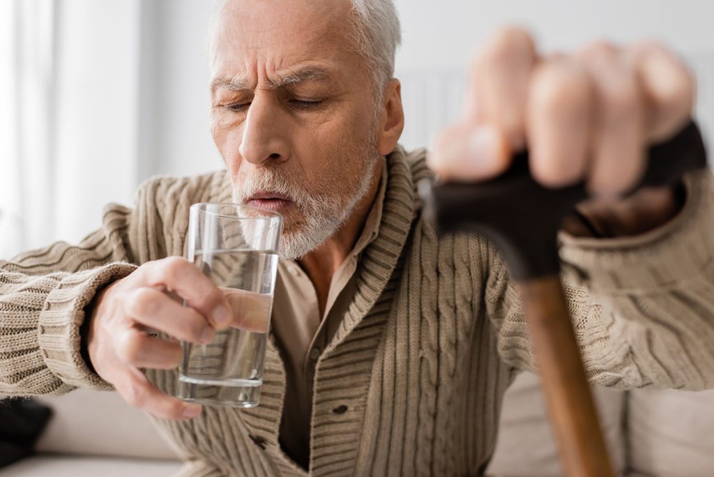 Older man about to drink cup of water
