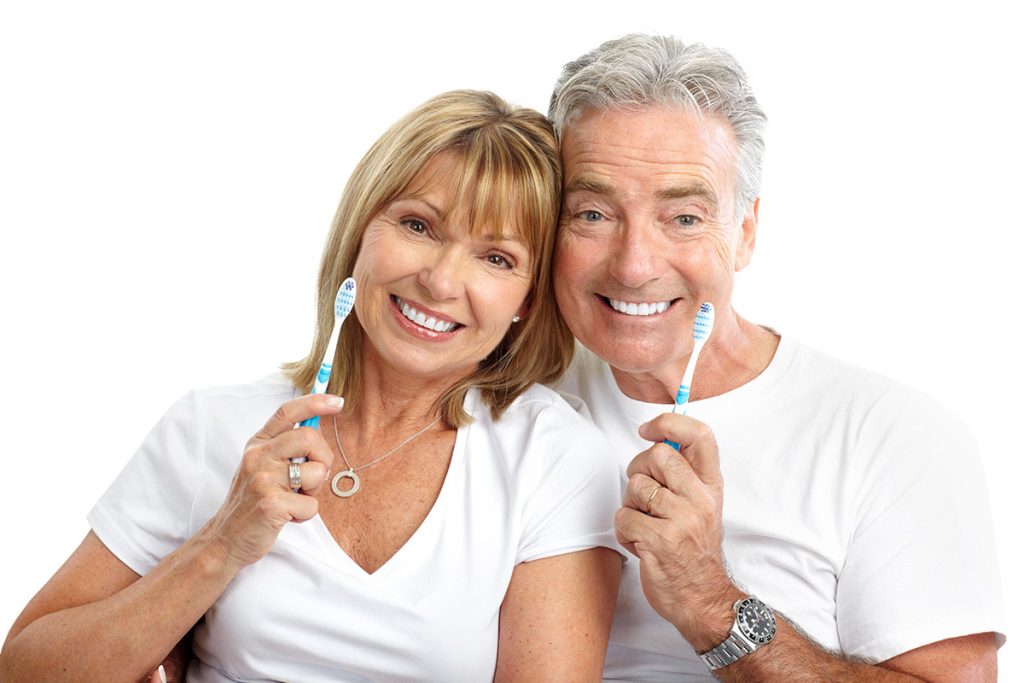 Senior couple smiling holding toothbrushes
