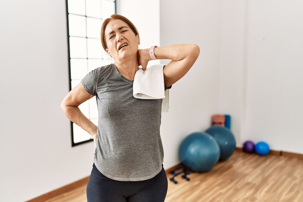 Older woman suffering from neck pain during workout 