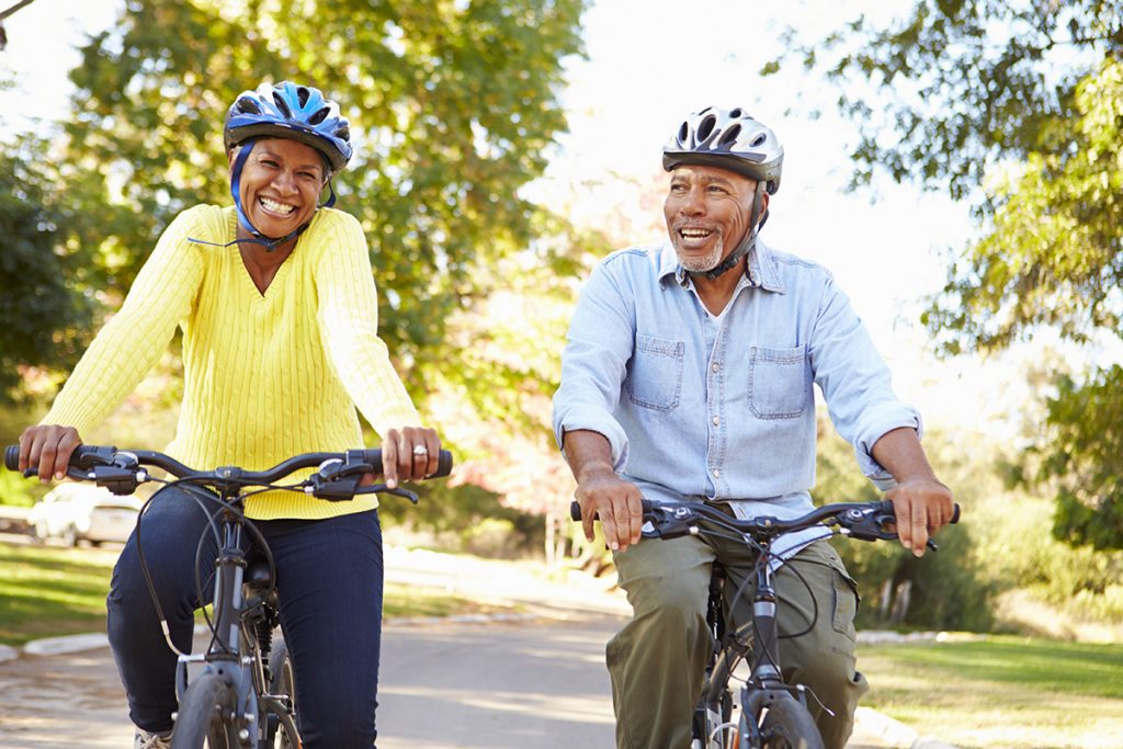 Older black couple cycling together in park