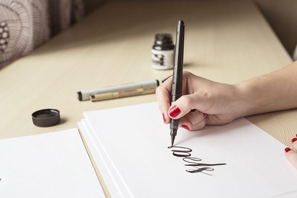 Woman practicing calligraphy with inked pen