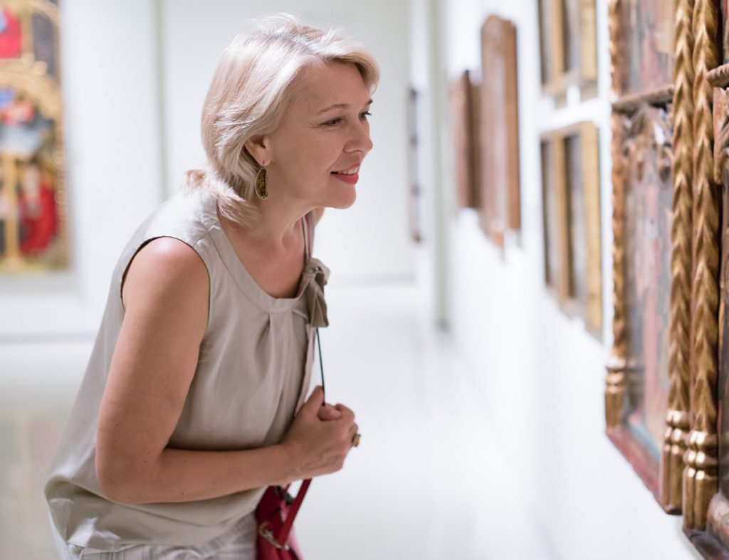 Older woman looking at paintings in museum