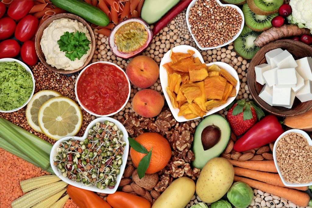 Healthy diet vegan food with grains, nuts, dips, bean curd, fruit, vegetables, legumes & spice.