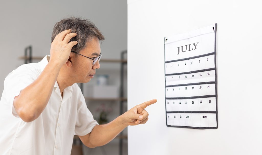 Confused Senior Man With Looking At Wall Calendar