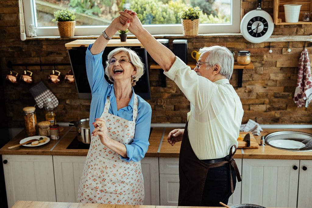 cheerful older couple dancing happy in the kitchen