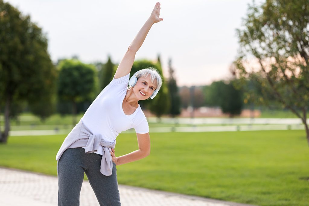 active woman stretching listening to music through headphones outdoors