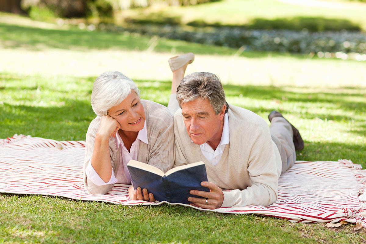 older couple reading at the park together