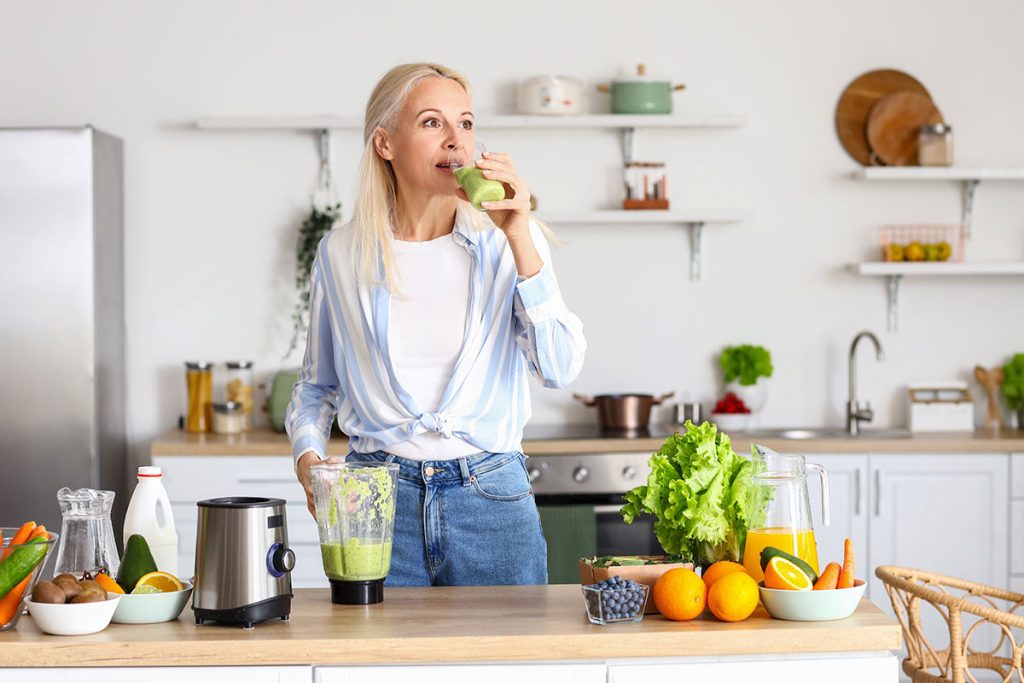 woman drinking healthy smoothie in kitchen