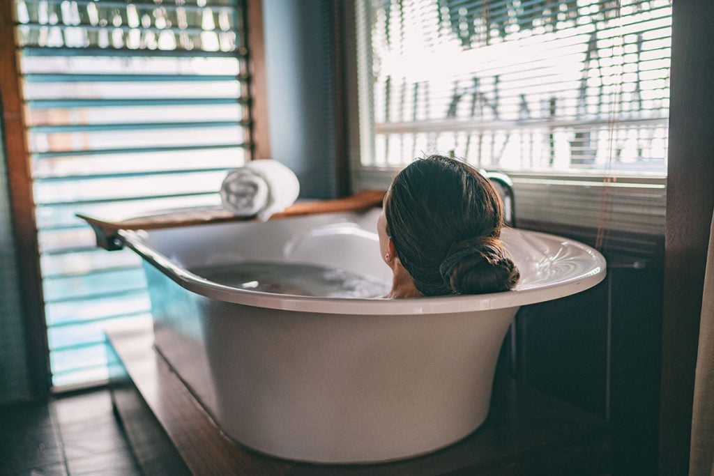 Bath taking woman relaxing in bathtub of hotel room 