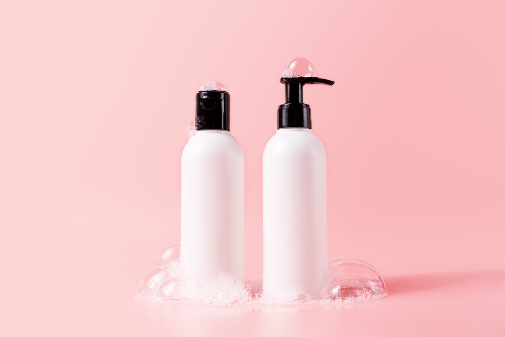 Shampoo and hair conditioner bottle with soapy bubbles. 
