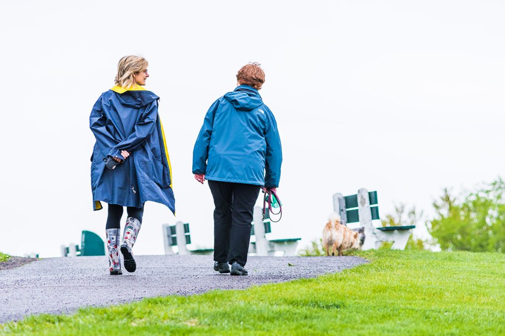 two friends walking in chilly weather with light rain jackets