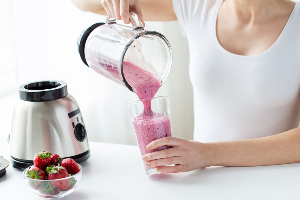 woman making fruit smoothie with blender