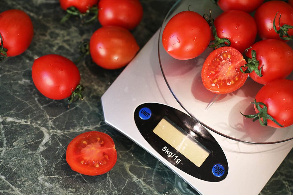 Fresh tomatoes on kitchen scales weighing and measuring