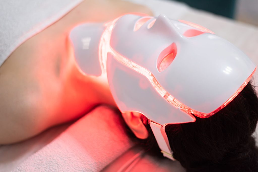 Woman lying down with an LED mask for skin care 