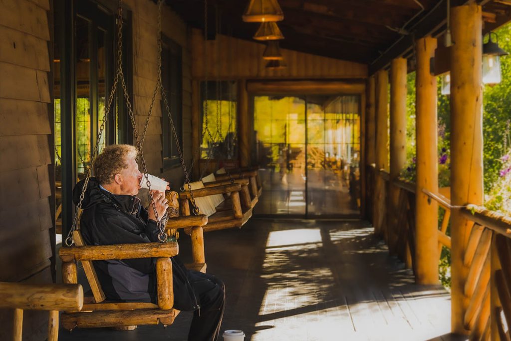 Senior man drinks hot beverage on  on the porch in autumn