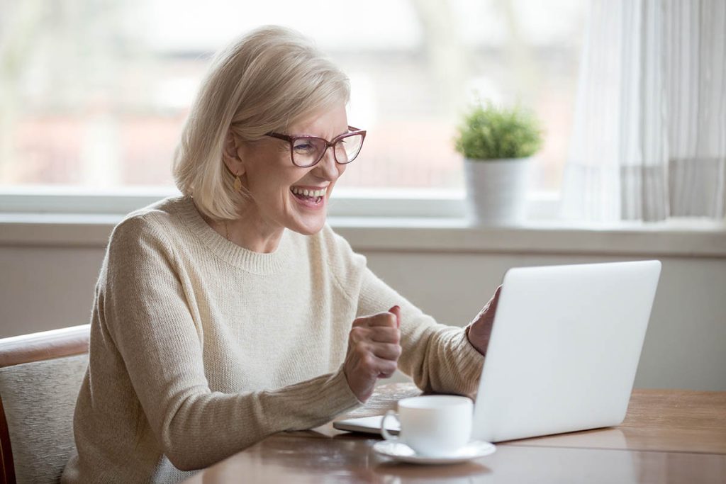 Older woman happy and focused on her work laptop