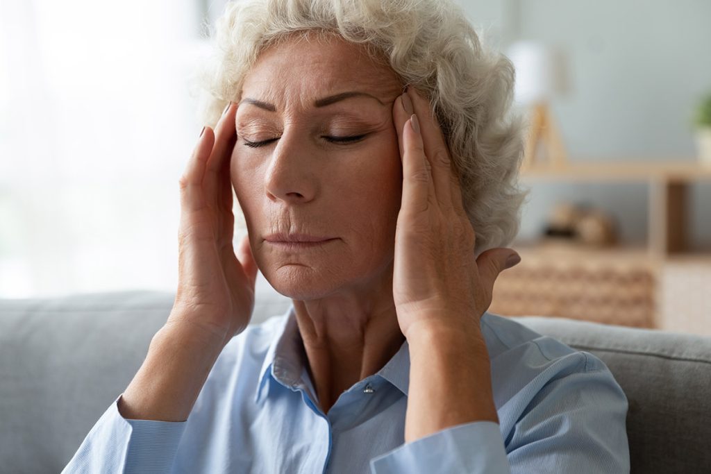 Close up face of elderly 65s woman massaging temples closed eyes reduces intense intermittent throbbing headache chronic terrible migraine, hormonal imbalance