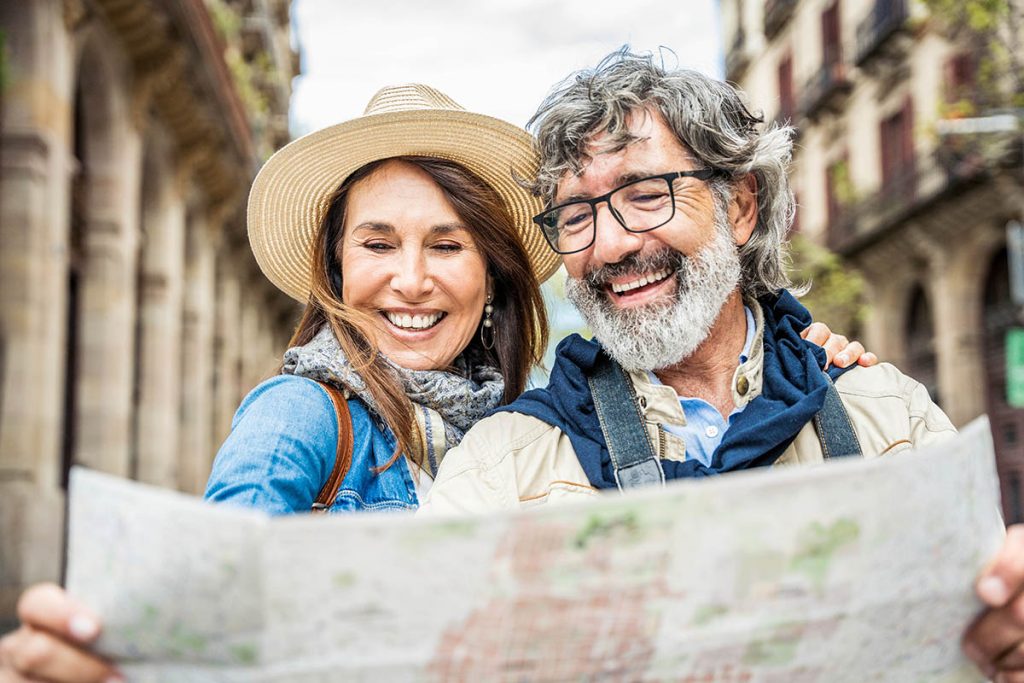 Married couple of tourists sightseeing city street with map